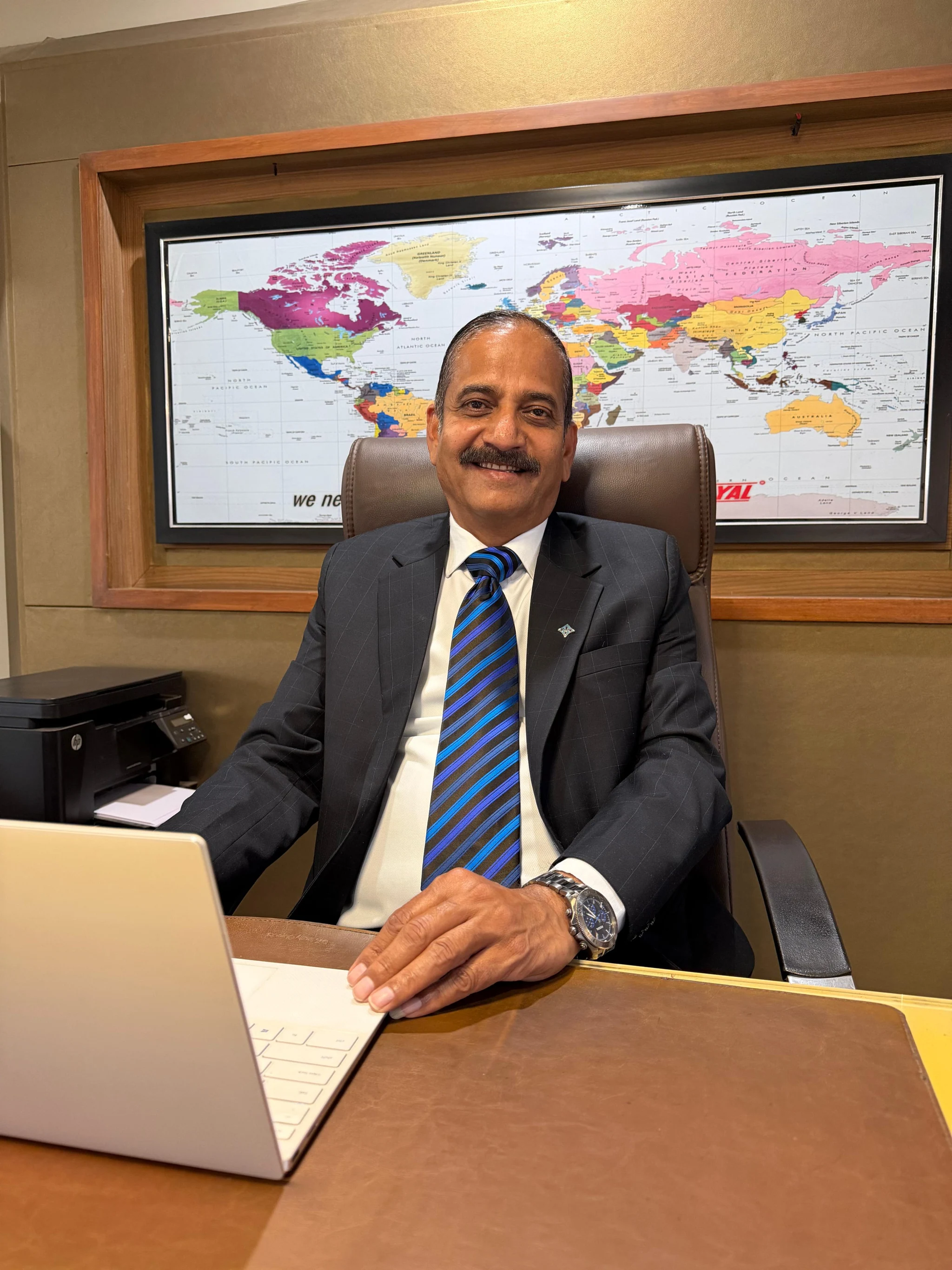 Choyal leader seated in front of a world map
